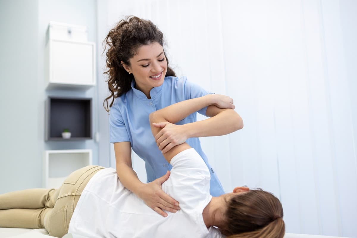 Physical therapist assisting a patient with shoulder exercises during therapy session.